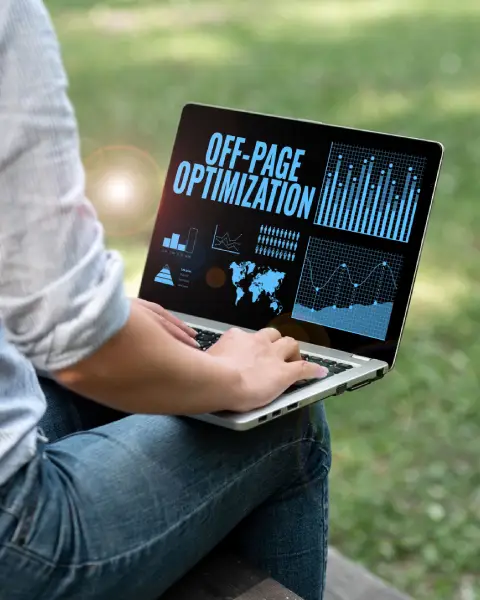 A person sitting outdoors on a bench, typing on a laptop screen that displays the bold blue text "OFF-PAGE OPTIMIZATION" surrounded by digital marketing charts, graphs, and a world map